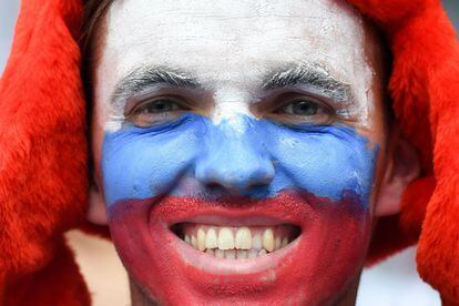Un joven sonríe con la cara pintada de la bandera de Rusia antes de la ceremonia.