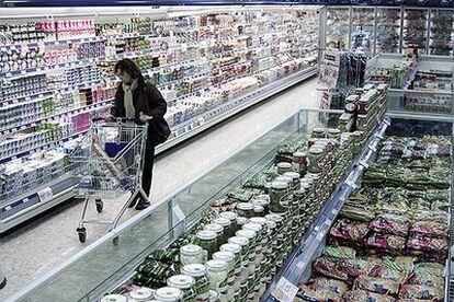 Una mujer recorre las estanterías de alimentos de un supermercado.
