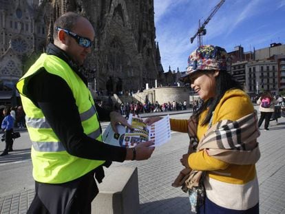 Un 'mosso' repartiendo dípticos a una turista en la Sagrada Familia. 