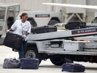 Una trabajadora de handling repartiendo maletas.