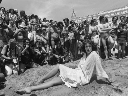Sylvia Kristel posa en la playa de Cannes en 1977 rodeada de hombres que observan.