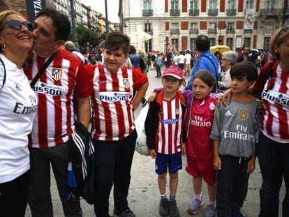 Un grupo de seguidores del Atlético junto a unos aficionados del Real Madrid, en la Puerta del Sol.
