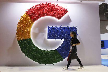 Una mujer camina delante del logo de Google.