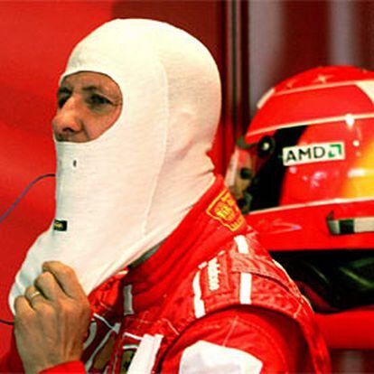 Michael Schumacher se coloca la protección antes de ponerse el casco, en los momentos previos a los entrenamientos de hoy en Silverstone.
