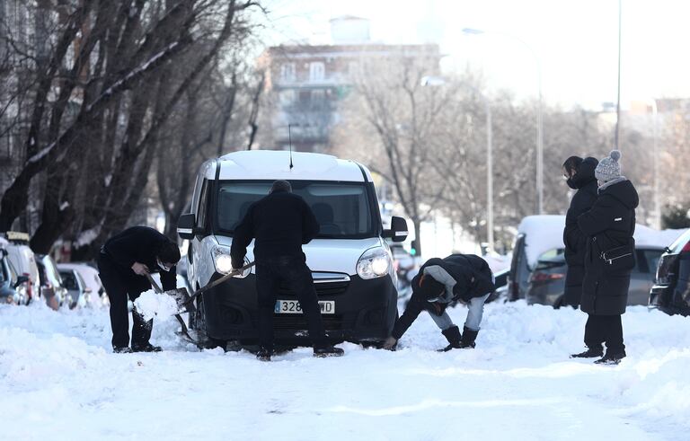 Vecinos del barrio de Pueblo Nuevo ayudan a un conductor a sacar su coche de la nieve