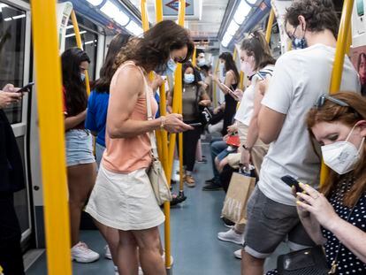 Grupo de personas consultando sus teléfonos móviles en un vagón del metro de Madrid.