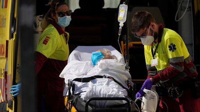 Healthcare workers wearing protective gear are seen with a patient on a stretcher near the emergency unit at 12 de Octubre hospital, amid the outbreak of the coronavirus disease (COVID-19), in Madrid, Spain August 14, 2020. REUTERS/Juan Medina