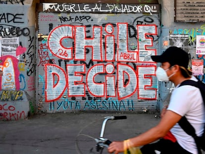 Un hombre en bicicleta pasa este viernes 23 de octubre delante de una pintada callejera que llama a votar en el plebiscito constitucional del domingo.