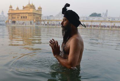 Un indio Sikh se baña de madrugada en el lago de agua bendita 'Sarovar' durante el Festival de Diwali en el Templo Dorado iluminado en Amritsar, India.