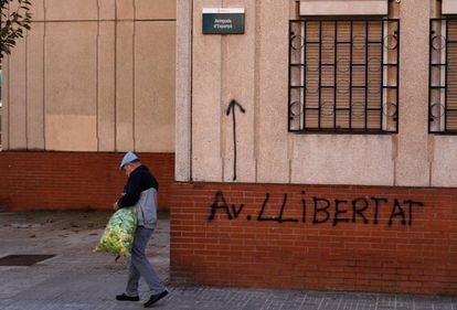 Un home passa davant de l'avinguda d'Espanya amb un grafiti que indica avinguda llibertat, a Cerdanyola (Vallès Occidental).