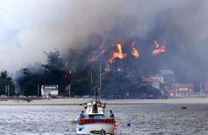 Un pesquero se aleja de la costa frente a la localidad de O &Eacute;zaro (Dumbr&iacute;a), en llamas por el incendio procedente de O Pindo.