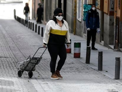 Una mujer con mascarilla y con carrito en una calle en Madrid.