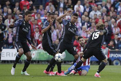 Carrasco, en el suelo, es flanqueado por los jugadores del Real Madrid.
