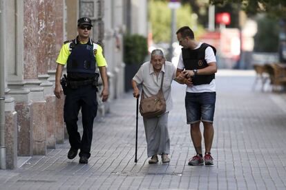 Efectivos policiales acompañando a una mujer mayor cerca del área en la que se ha producido el atentado terrorista en Las Ramblas de Barcelona.