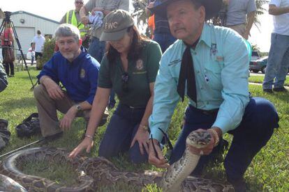 Varios miembros de la autoridad forestal de Florida sostienen una pit&oacute;n.  