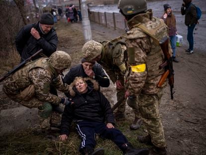 A semi-conscious woman is attended to by Ukrainian soldiers after crossing the Irpin river as fleeing the city in the outskirts of Kyiv, Ukraine, Saturday, March 5, 2022. (AP Photo/Emilio Morenatti)