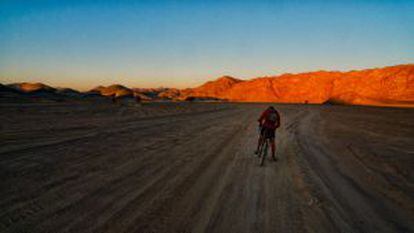 Un solitario ciclista cruza al amanecer un complicado tramo del desierto de Sudán.
