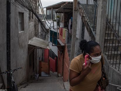 Una mujer con mascarilla utiliza su teléfono móvil en la favela de Paraisópolis, la más grande de São Paulo, el 6 de mayo de 2020.