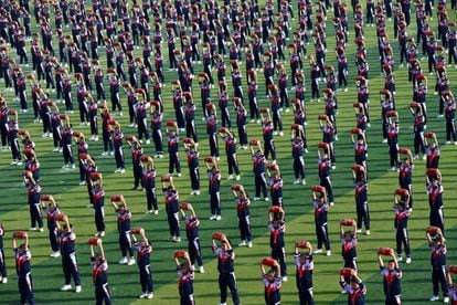 Un numeroso grupo de estudiantes actúa con instrumentos de percusión durante la ceremonia de inauguración de un encuentro deportivo en Xiangyang, provincia de Hubei (China).