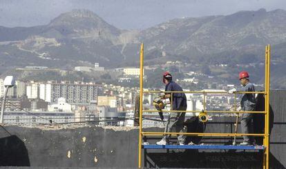 Unos obreros, en el andamio de una obra, en Ceuta.
