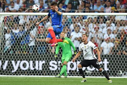 El jugador francés Olivier Giroud cabecea el balón ante el germano Benedikt Hoewedes. 
 