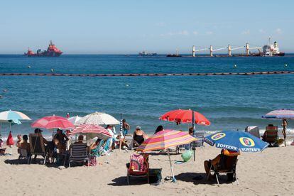  Bañistas en la playa de la Caleta, en Gibraltar, observan este martes el buque varado al este del Peñón, el 'OS 35'.
