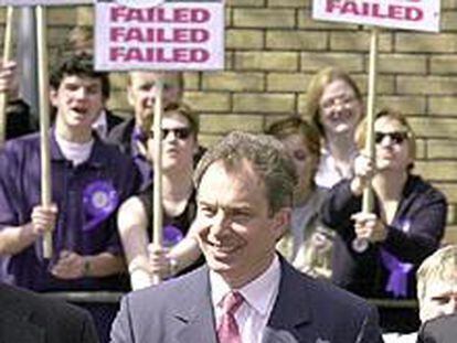 Tony Blair pasa ante un grupo de simpatizantes del Partido Conservador con carteles críticos con su gestión.