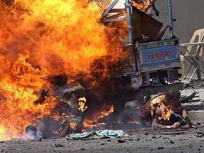Un hombre se quema y otro se arrastra lejos del fuego segundos después de la explosión de un coche bomba ayer en Bagdad.