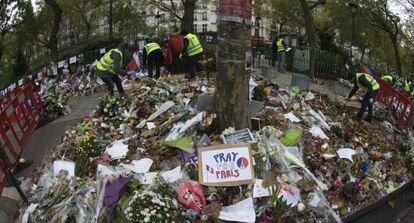 Empleados municipales recogen flores y objetos en memoria de las v&iacute;ctimas ante la sala Bataclan de Par&iacute;s. 