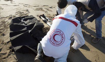 Voluntarios de la Media Luna Roja retiran el cadáver de un inmigrante llegado a una playa de Trípoli.