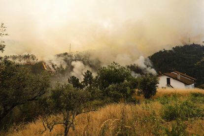 Vista del humo y las llamas cerca de las viviendas en la localidad de Cabreira, en Góis.