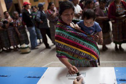 Una guatemalteca con su bebé deposita su voto en una urna ayer en San Juan Comalapa.