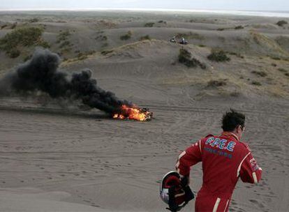 El copiloto belga Jean-Paul Forthome corre mientras su coche se incendia en las dunas de Nihuil.