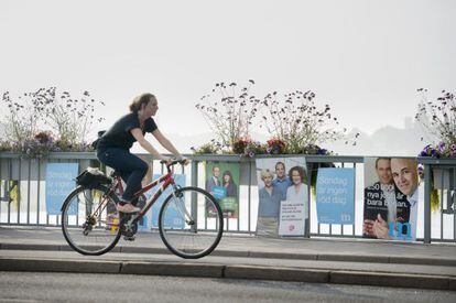 Una ciclista pasa ante carteles electorales de socialdemócratas y moderados suecos en Estocolmo.