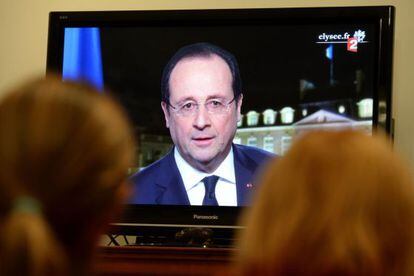 Dos personas siguen el discurso de Hollande.