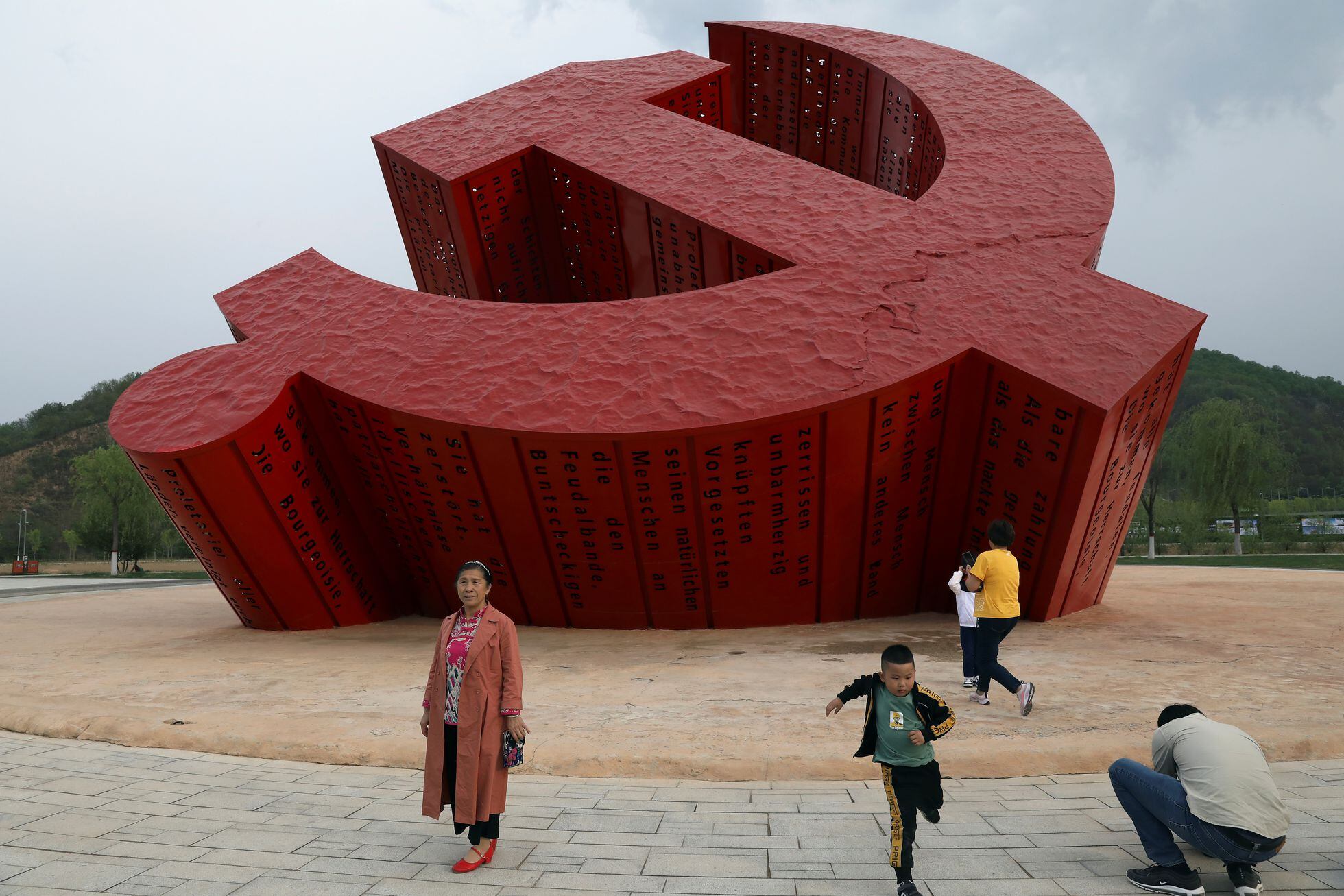 Turistas chinos posan frente a un emblema del Partido Comunista en Nanniwan, una antigua base revolucionaria 