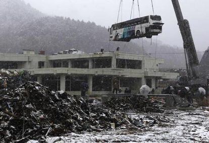 Un autobús arrastrado por el tsunami es levantado por una grúa en Ishinomaki, en la prefectura de Miyagi, el 10 de marzo de 2012.
