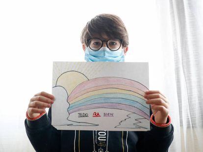 Un niño con mascarilla enseña un dibujo que ha hecho de un arcoiris y la frase 'Todo irá bien'.