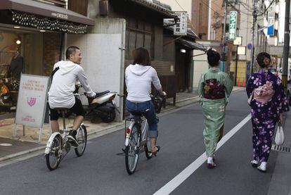 Ciclistas y 'geishas' en el centro de Kioto (Japón).