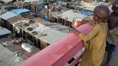 Unos niños recaudan dinero y comida con una lata entre las infraviviendas del suburbio de Colobane, en Dakar (Senegal).