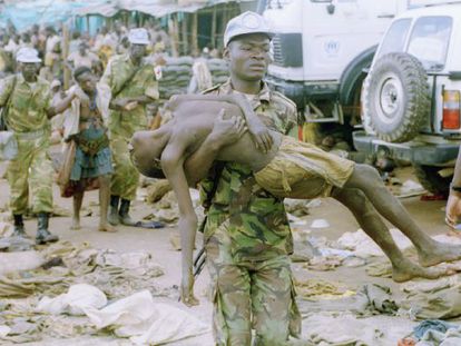 Un casco azul de la ONU lleva en brazos a un refugiado en el campo de Kibeho, al suroeste de Ruanda, en abril de 1995.  