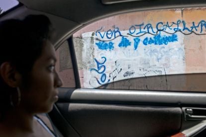 Una mujer pasa en frente de una pintada hecha por la Mara Salvatrucha en su comunidad que dice “ver, oír, callar si la vida quieres salvar” y la insignia MS.