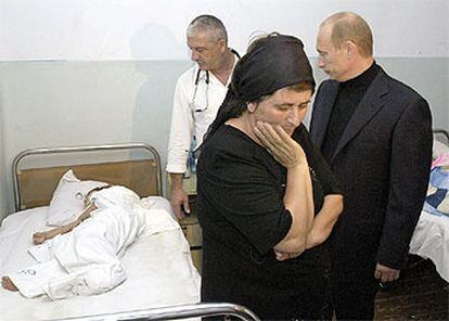 El presidente ruso, Vladímir Putin (derecha), observa a uno de los niños heridos durante el secuestro de la escuela de Beslán.