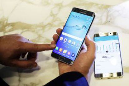 Un hombre sujeta el nuevo Samsung Galaxy S6 Edge Plus. Sobre la mesa, el Note 5