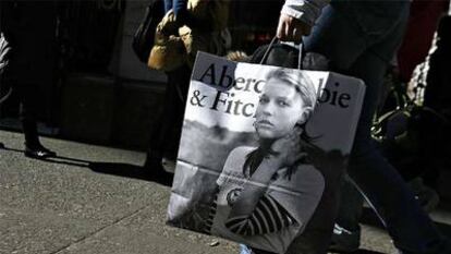 Una mujer camina con una bolsa de una tienda de Abercrombie.