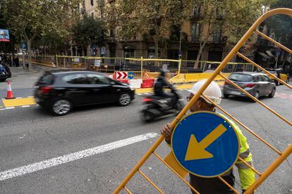 Momento en el que varios operarios ponen vallas para indicar que la calle de Consell de Cent, a la altura de Pau Claris, en Barcelona, ya no se puede cruzar en línea recta y es obligatorio girar en cada esquina.