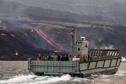 Transporte marítimo de la Armada en el que nueve agricultores accedieron este jueves a las plataneras cerca de Puerto Naos. Al fondo, la lava cae sobre la playa de Los Guirres.