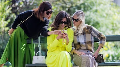 Tres mujeres revisan un teléfono móvil.