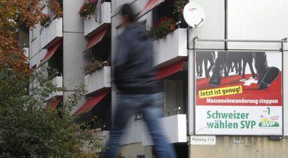 Un transeúnte pasa ante un cartel del derechista SVP/UDC que llama a “frenar la inmigración masiva”
