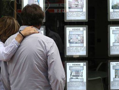 Una pareja observa anuncios de pisos en una inmobiliaria en Madrid.